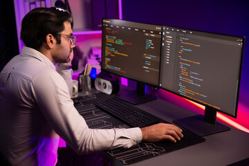 Working smart IT developer analyzing data software development on two pc screen, creating application program updated version online website page system online at neon light cyber office. Surmise.