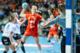 Detail of goalkeeper's hand  and handball game in the background.