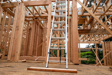 Wall Mural - Interior new house construction at wood framing stage, aluminum extension ladder propped up on 2nd floor support truss beams
