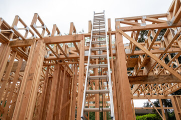 Wall Mural - Interior new house construction at wood framing stage, aluminum extension ladder propped up on 2nd floor support truss beams
