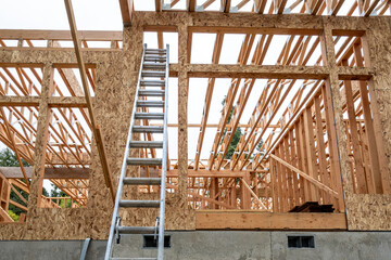Wall Mural - Exterior new house construction at wood framing stage, aluminum extension ladder propped up against back wall, early days on residential job site
