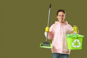 Wall Mural - Young man with broom and recycle bin on green background