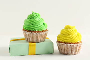 Wall Mural - Tasty colorful cupcakes with gift box on white background