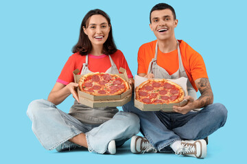 Young couple with tasty pepperoni pizza on blue background