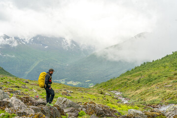 male hiker in the fjord of andalsnes - isfjorden in norway hiking on a rainy cloudy day in the mount