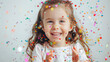 © NooPaew - Little girl laughing and playing with colorful confetti, creating a joyful scene on a white background
