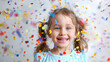 © NooPaew - Happy little girl with colorful confetti falling around her, smiling widely on a white background