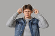 © Pixel-Shot - Young man with headphones suffering from headache on grey background