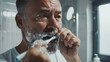© NooPaew - Close-up of a middle-aged European man brushing teeth in the bathroom, morning hygiene routine before mirror