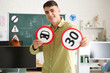 © Pixel-Shot - Young man with road signs at driving school