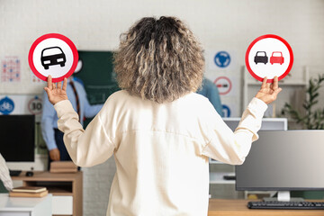 Sticker - Mature woman with road signs at driving school, back view