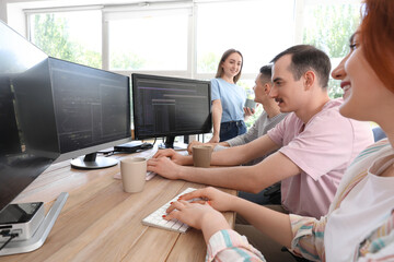 Team of young programmers working at table in office