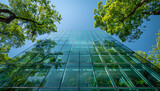 A clear glass building with green trees and a blue sky