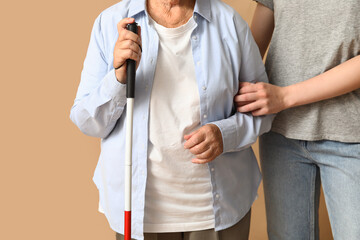 Young woman with blind grandmother on beige background, closeup