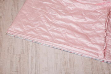 A close-up of pink quilted fabric beside a measuring tape, perfect for textile and sewing projects.