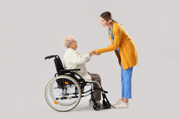 Sticker - Senior woman in wheelchair with nurse holding hands on light background