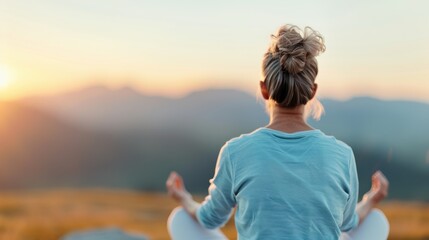 A woman meditates outdoors at sunrise, facing the serene landscape. Her calm posture and the peaceful setting evoke a sense of tranquility and mindfulness amidst nature.