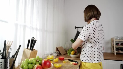 Wall Mural - Caucasian mother put vegetable in bowl making a salad for breakfast while happy mom preparing fresh ingredients for salad at modern kitchen. House keeper cooking healthy meal. Care concept. Pedagogy.