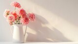 Coral pink dahlias in a jug on a white shelf against a neutral wall