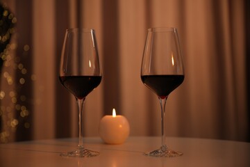 Canvas Print - Burning candle and wine in glasses on table indoors