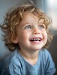 © Dyeru - Joyful Child with Curly Hair and Bright Blue Eyes Smiling Indoors