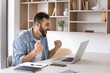 © fizkes - Happy businessman excited with good news making winner hands at laptop, shouting yes, laughing, enjoying job success, work achievement, winning price, sitting at office workplace