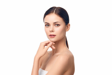 Wall Mural - Photo of a beautiful young woman posing with her hand on her chin and looking at the camera, isolated on white background