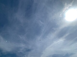 Wall Mural - image of a sky with white clouds and the bright light of the sun.
