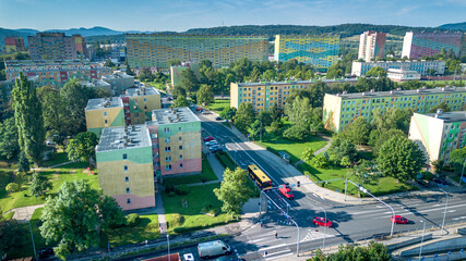 Colorful residential buildings in a vibrant neighborhood with green spaces and roadways on a sunny day