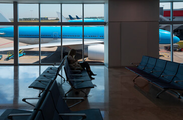 Wall Mural - Silhouette of young woman working on laptop and waiting for flight in the Airport - Amsterdam Airport Schiphol  - Amsterdam, NETHERLANDS