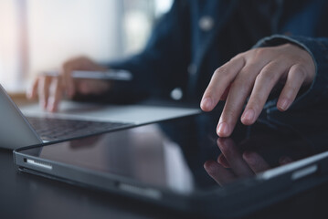 Wall Mural - close up of business woman using digital tablet during online working on laptop computer on office t