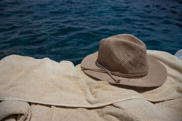 Summer hat and towel on the beach. Summer accessories for vacation on the background of the sea