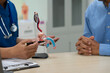 © NanSan - A male doctor sits and works at the table, explaining the urinary system and penile health to anxious patients. Consultations cover sexual matters, sterilization, and other related concerns.