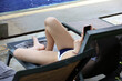 © Oleg - Girl in swimsuit lying with smartphone in hands in deck chair near swimming pool. Summer holidays, girl using mobile phone on beach resort