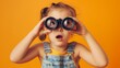 © BB_Stock - Girl looks through binoculars with an excited or shocked expression on an orange background.