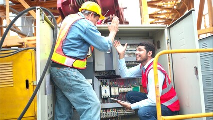 Wall Mural - Bothe of electrical engineer inspects the electrical control board of a crane before putting it to use on a construction site