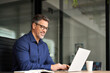 © insta_photos - Busy happy middle aged business man company manager investor working online on computer sitting at office desk. Mature older professional businessman executive using laptop at corporate workplace.