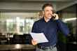 © insta_photos - Busy older business man hr manager of middle age making call in office. Mature senior businessman executive, lawyer or entrepreneur holding documents talking on the phone at work consulting client.
