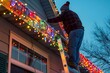 © Joaquin Corbalan - A man on a ladder is putting up Christmas lights on the eaves of a house. Festive holiday decoration.