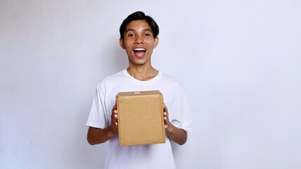 Asian young man happy wearing white shirt gesture holding package box