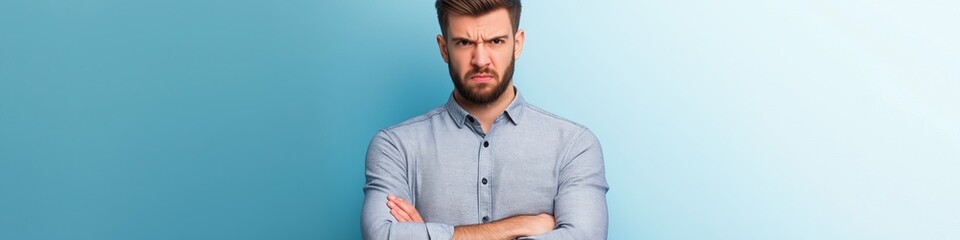 A man with a beard and glasses is standing with his arms crossed and looking away. He is in a bad mood or feeling upset