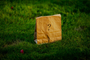 Surprise mysterious paper back with a question mark close up on green grass for a magician kit