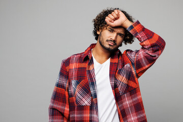 Wall Mural - Young sad sick ill tired exhausted Indian man he wearing red shirt casual clothes put hand on forehead suffer from headache isolated on plain grey color background studio portrait. Lifestyle concept.