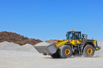 Front-end loader (bucket loader, payloader, high lift, scoop, shovel dozer, skid-steer, skip loader, tractor loader or wheel loader) moving ore, mine, Outback Western Australia