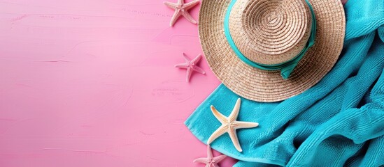 Fototapete - Top down summer holiday theme with a pink background featuring a straw hat blue towel and starfish ideal for text or images. Creative banner. Copyspace image