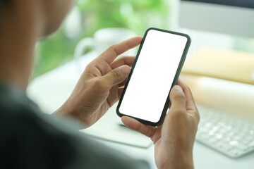 Wall Mural - young man holding mockup smart phone with white empty screen. close up view.