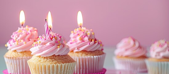 Aufkleber - Pink background with birthday cupcakes featuring lit candles Copy space image available