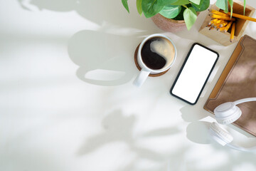 Wall Mural - Modern workplace with smart phone, notebook and coffee cup on white table. Top view with copy space.