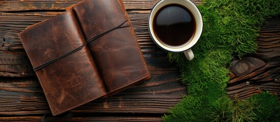 Poster - Top view of a set of hard leather covered diaries or notebooks placed on a wooden surface with a cup of coffee and vibrant green moss providing ample copy space for an image