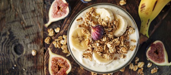 Aufkleber - Top view of a glass of homemade granola topped with yogurt fresh bananas and figs on a wooden surface offering copy space image